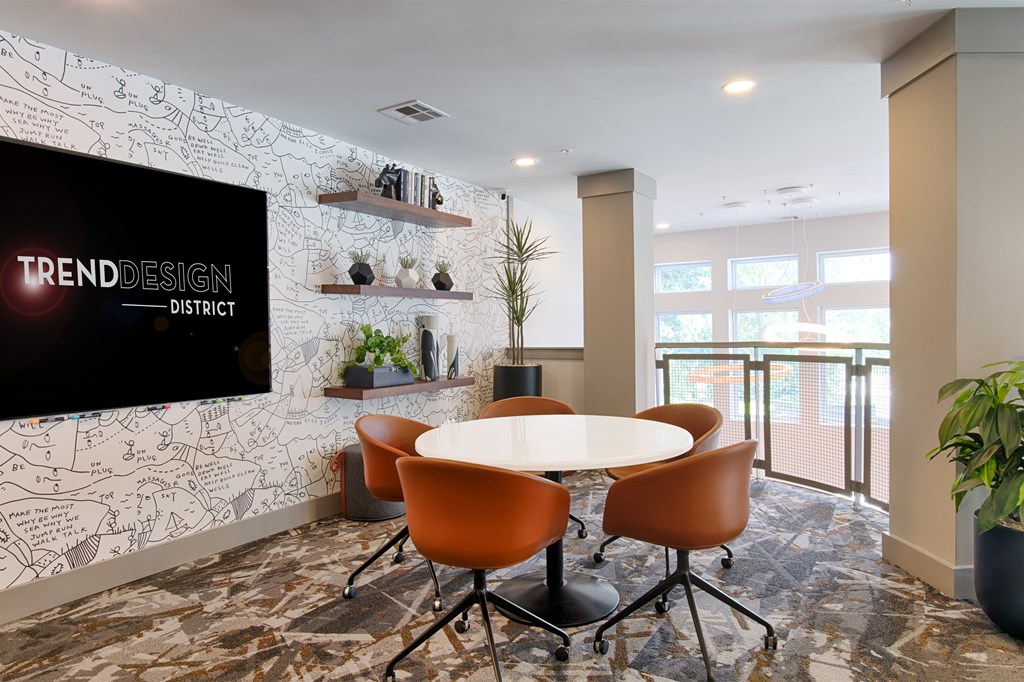 A conference room with a white table and chairs, a blackboard with the word "TRENDDESIGN" written on it, and a plant in a pot.