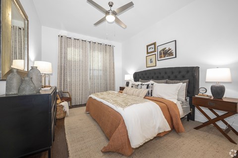A bedroom with a bed, nightstand, and a ceiling fan.