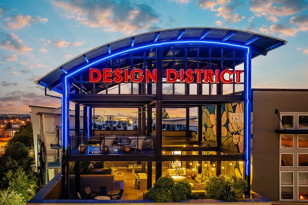 A modern building with a glass facade and a blue neon sign that reads "Design District".