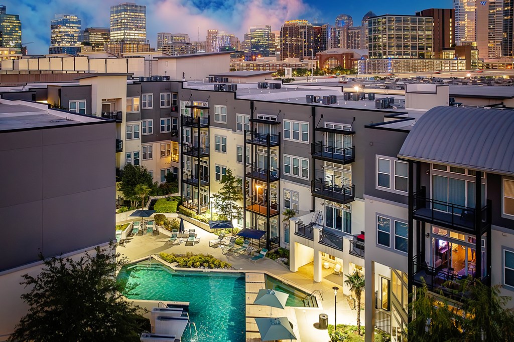 A view of a pool and apartment complex at dusk.