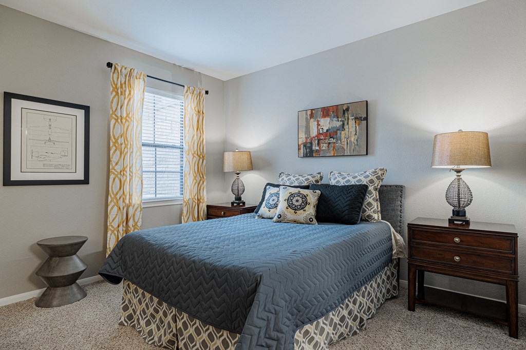 a bedroom with a bed and two lamps and a window