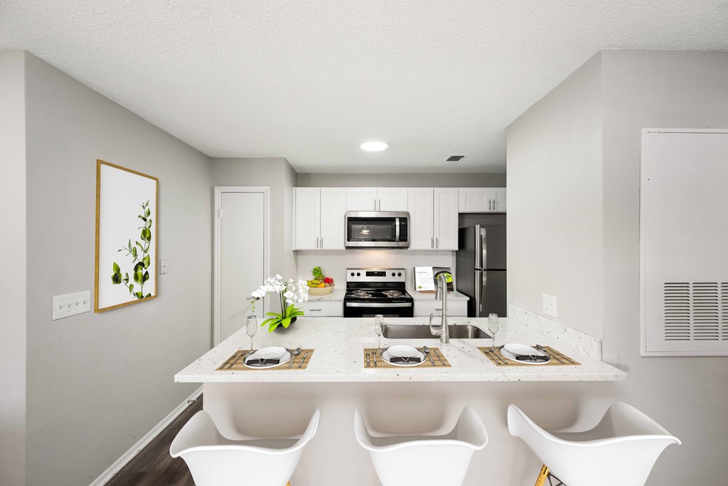 a kitchen with white cabinets and a white island with four white chairs