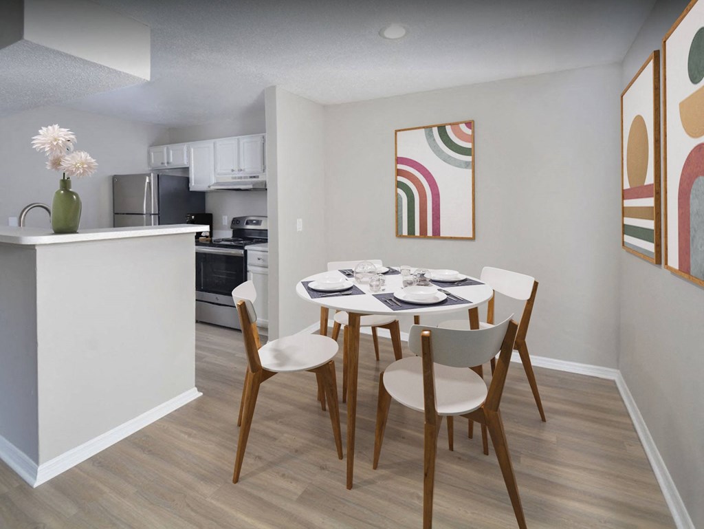 a dining area with a table and chairs and a kitchen in the background
