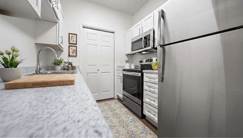 A kitchen with a refrigerator, oven, and sink.