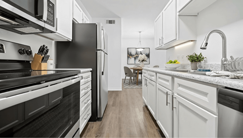 A modern kitchen with black and white appliances and wooden floors.