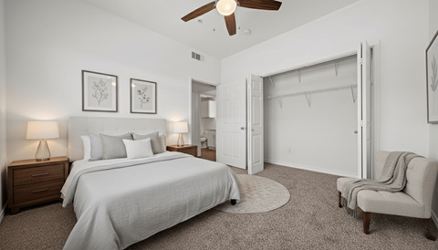 A bedroom with a large bed, a chair, and a ceiling fan.