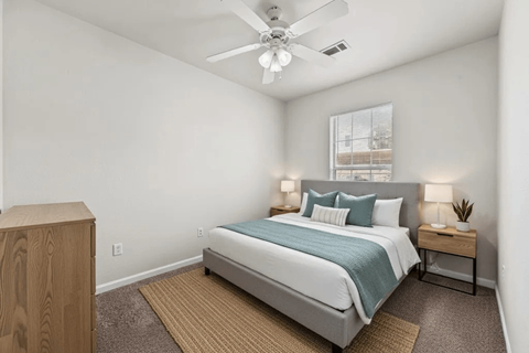 A bedroom with a bed, nightstand, and a ceiling fan.