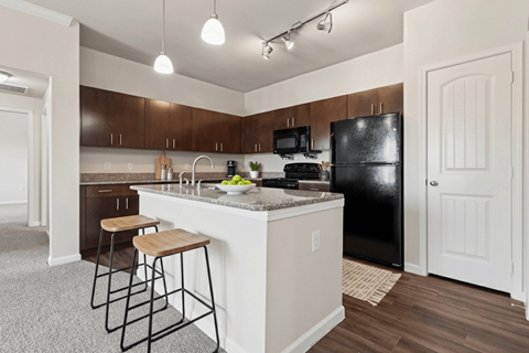 A kitchen with a black refrigerator and white countertops.