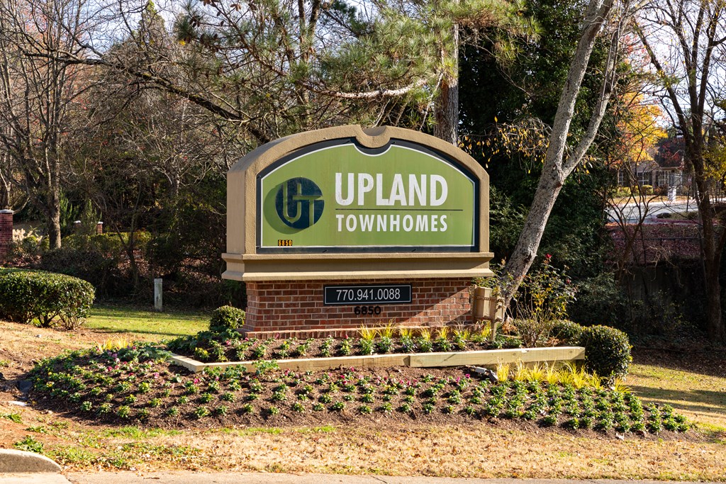 a sign for upland townhomes with trees in the background