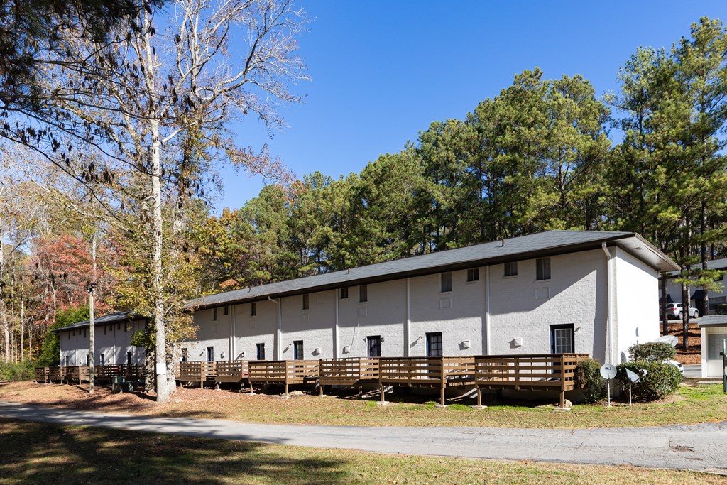 an image of the front of a white building with a wood deck in front of it