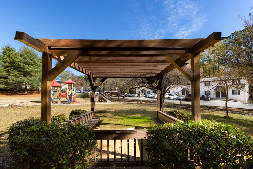 a pergola in a park with a playground in the background