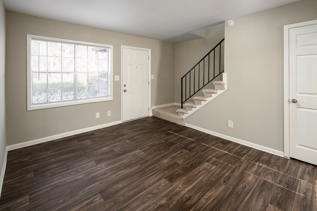a bedroom with hardwood floors and a staircase