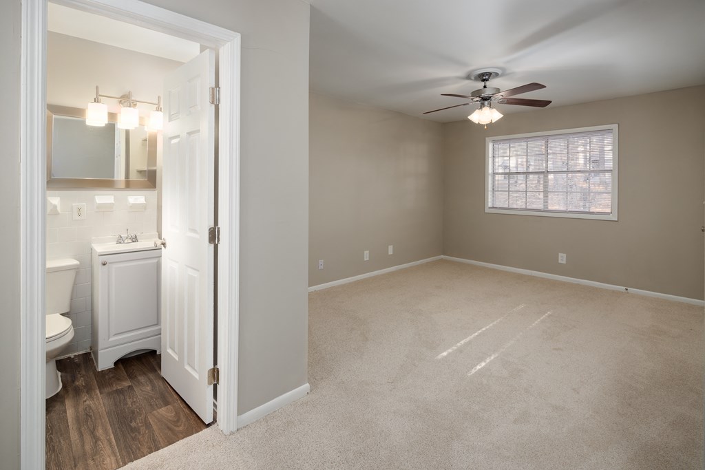 a bedroom with a ceiling fan and a bathroom