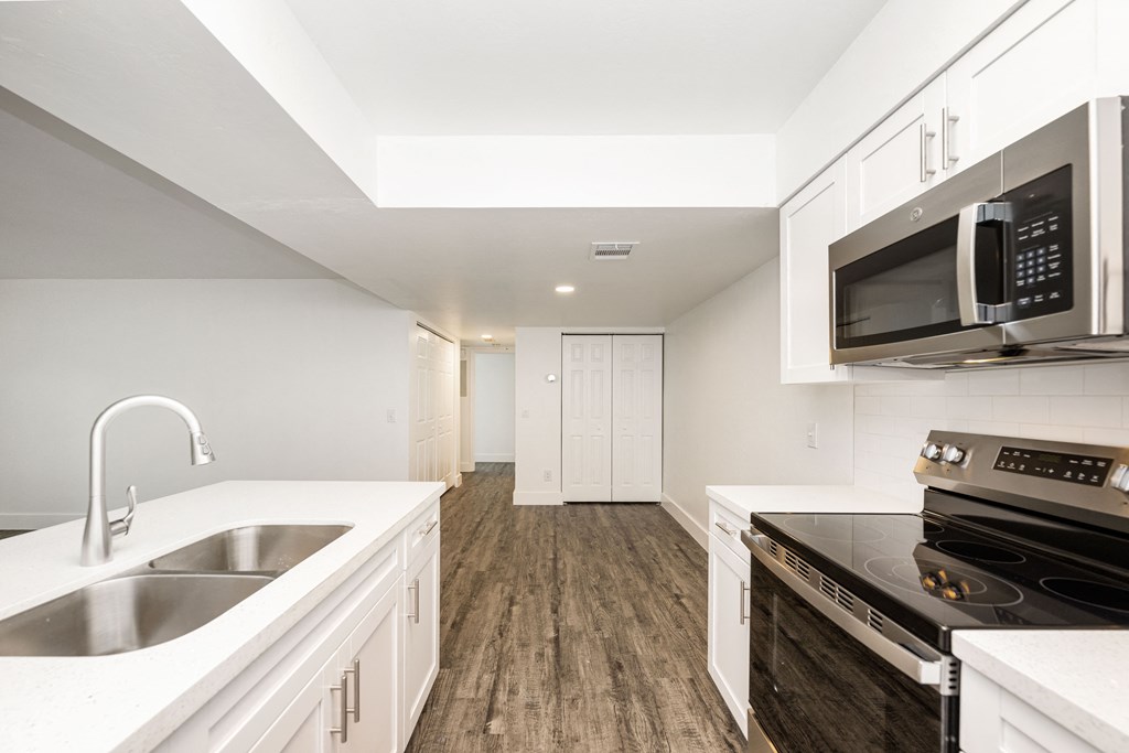 a kitchen with white cabinets and black appliances and a sink