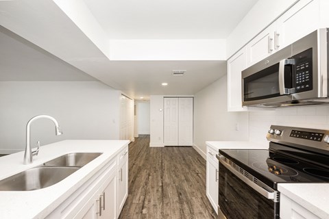 a kitchen with white cabinets and black appliances and a sink