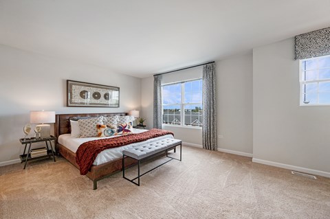 A bedroom with a large bed and a window with curtains.