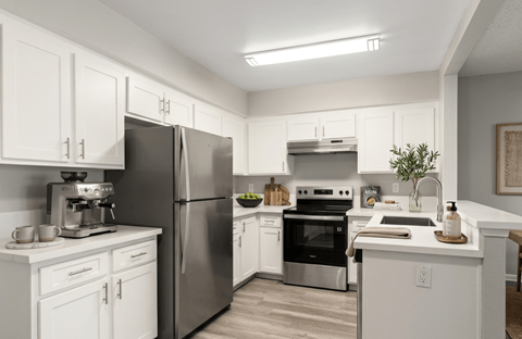A kitchen with white cabinets and stainless steel appliances.