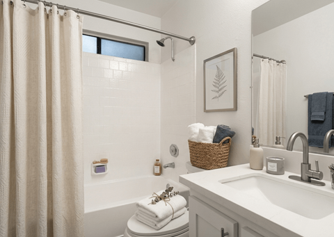 A bathroom with a white tub, sink, and shower curtain.