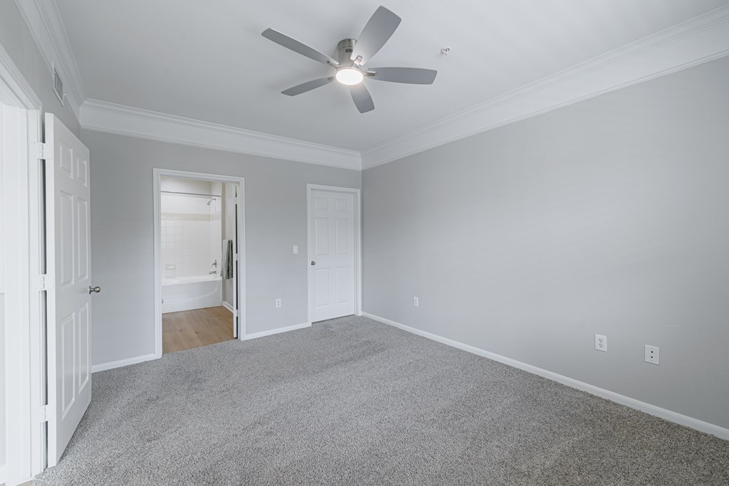 A room with a ceiling fan and carpeted floor.