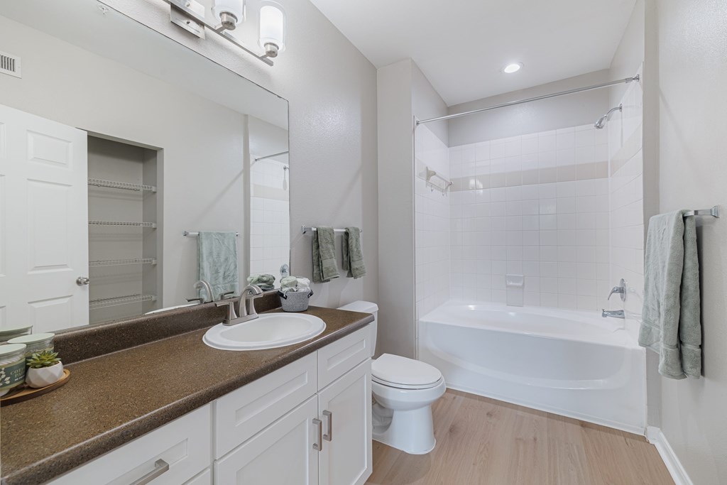 A white bathroom with a brown counter top and a white toilet.