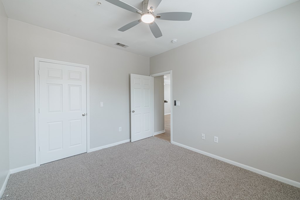 A room with a ceiling fan and two doors.