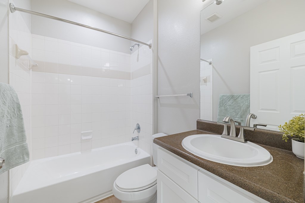 A white toilet sits next to a white bathtub in a bathroom.