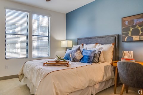 a bedroom with a large bed and two windows