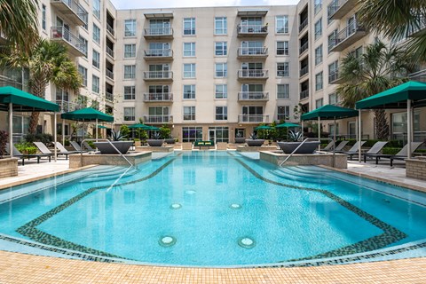 A large swimming pool in front of a multi-story apartment building.