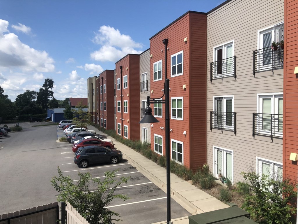 a row of apartment buildings with cars parked in a parking lot