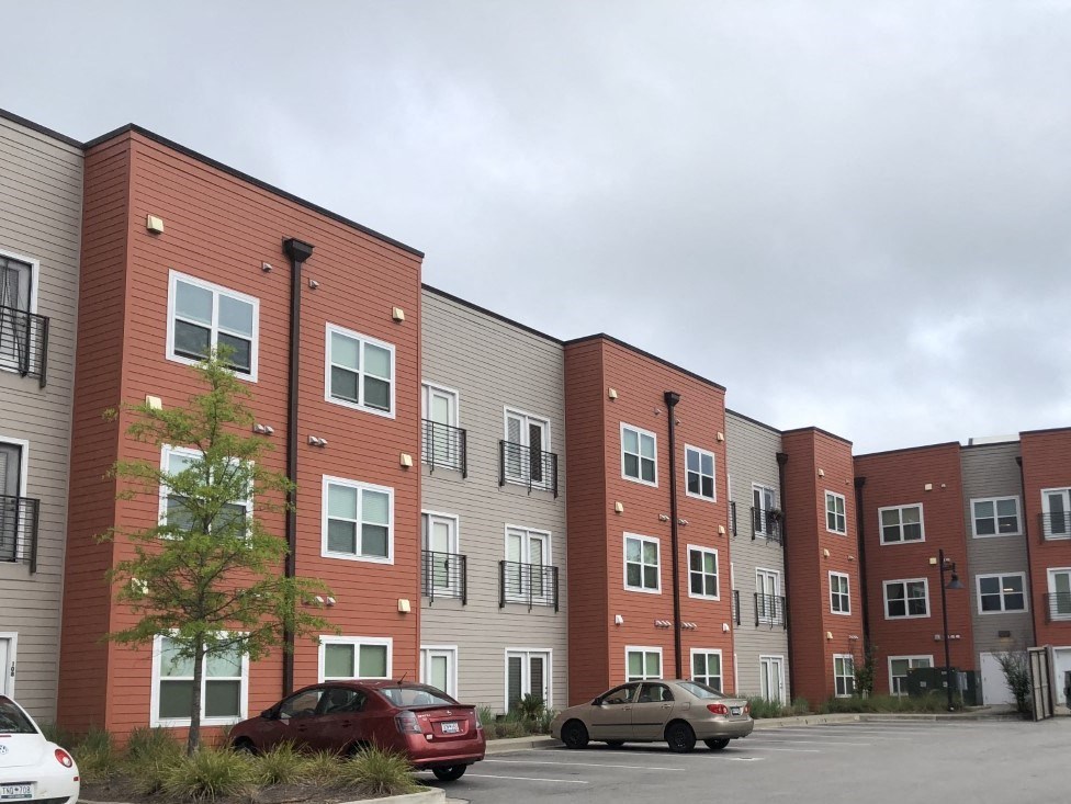 an exterior view of an apartment building in a parking lot