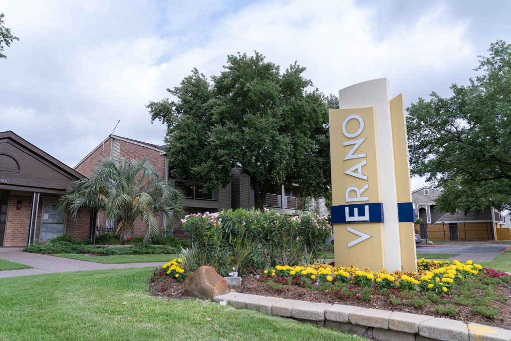 a building with a sign in front of a yard with flowers