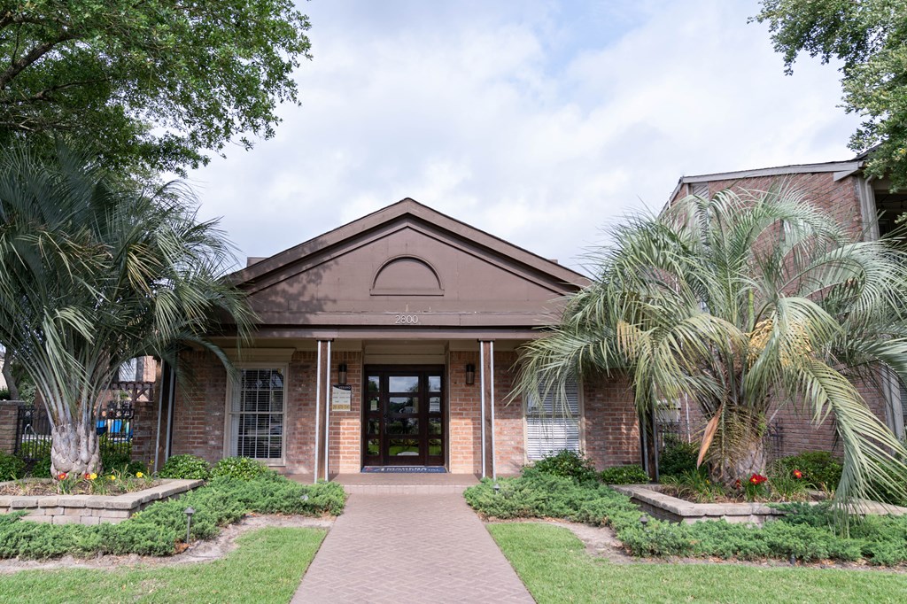 the front of a brick building with palm trees