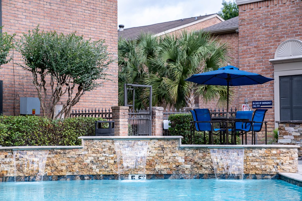 a swimming pool with chairs and an umbrella in front of a house