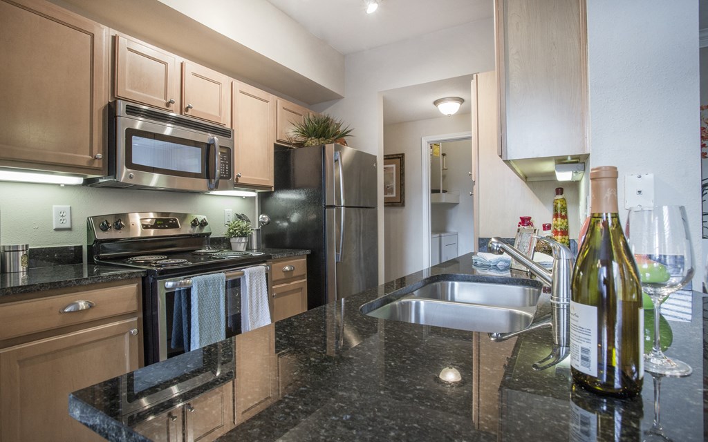 A kitchen with a black granite counter top and wooden cabinets.