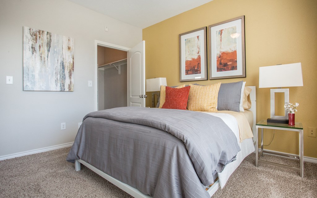A bedroom with a bed, nightstand, and two framed pictures on the wall.