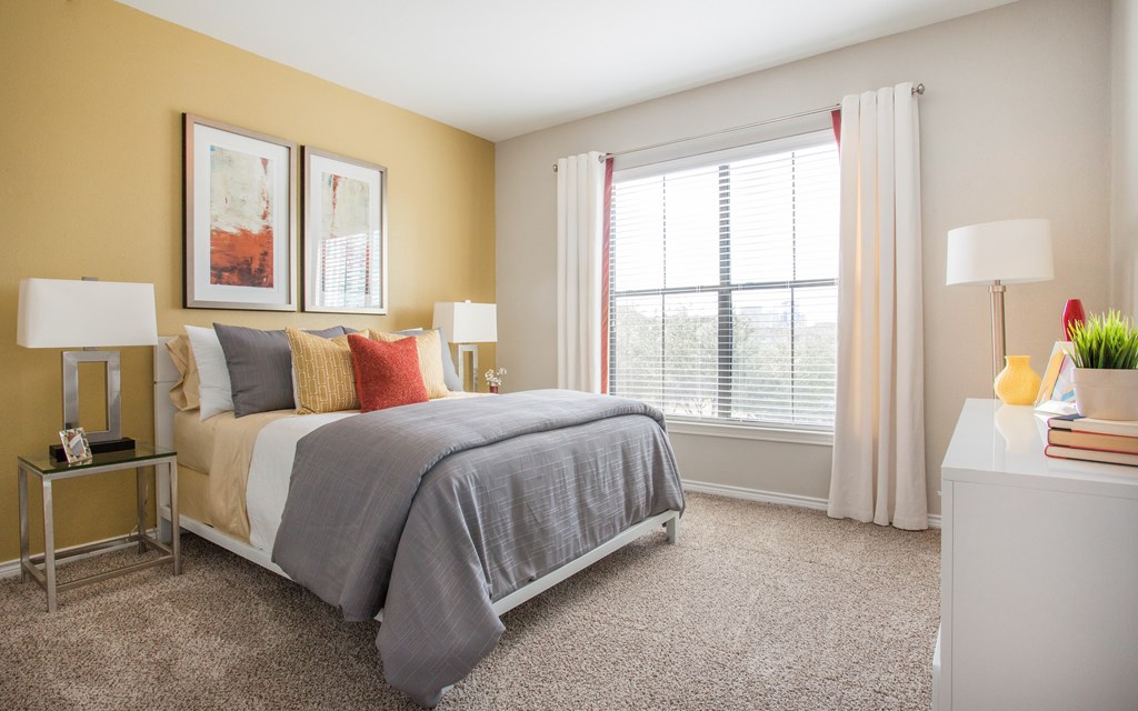 A bedroom with a bed, nightstands, and a window.