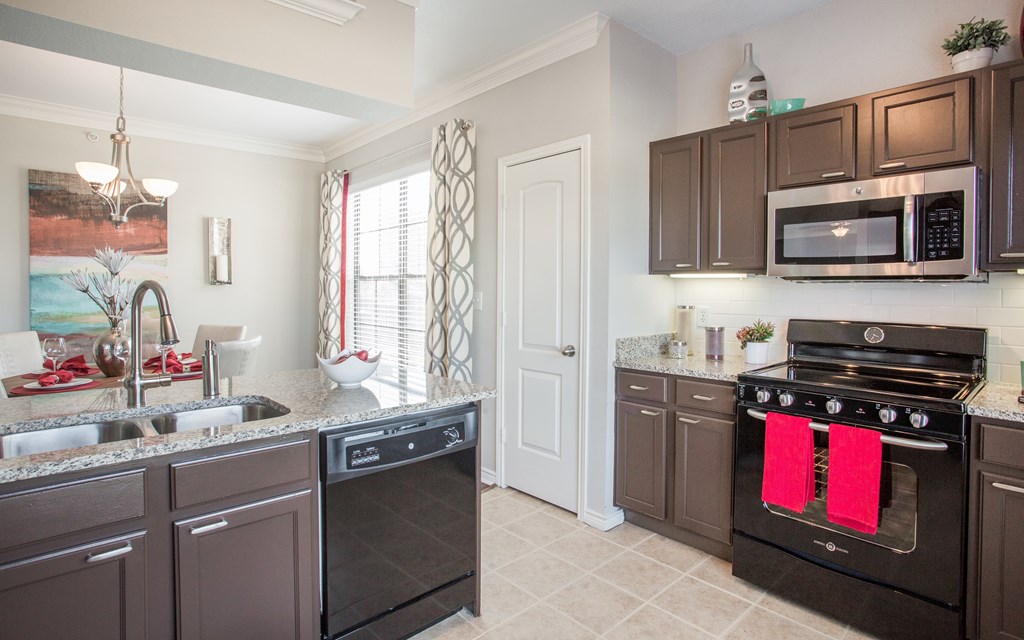 A kitchen with brown cabinets and black appliances.