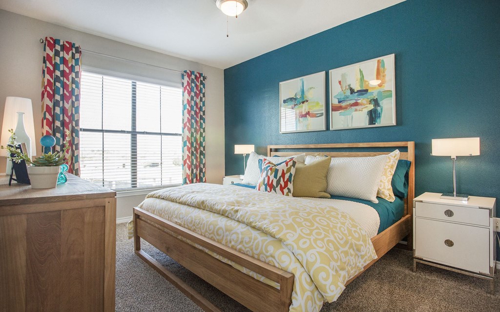 A bedroom with a bed, nightstand, and a window with curtains.