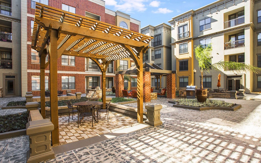 A patio with a table and chairs under a wooden pergola.
