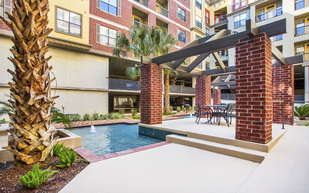 A pool area with a palm tree and a brick structure.