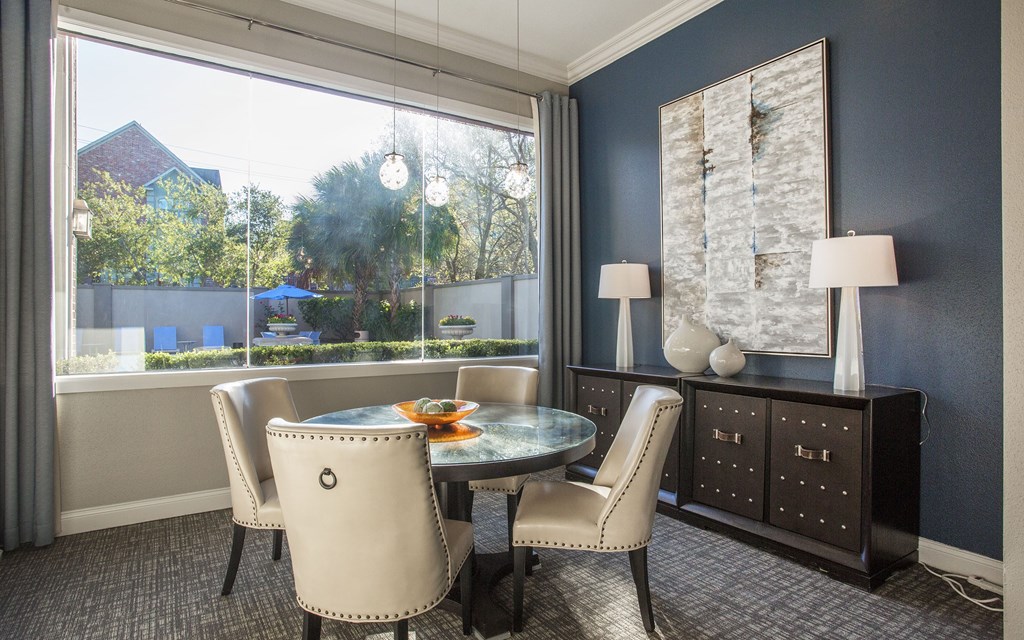A dining room with a table set for two and a view of a backyard.