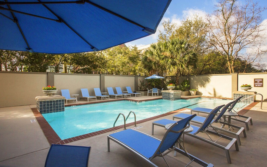 A pool with blue lounge chairs and a blue umbrella.