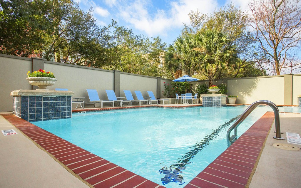 A pool with a red brick border and a person swimming in it.