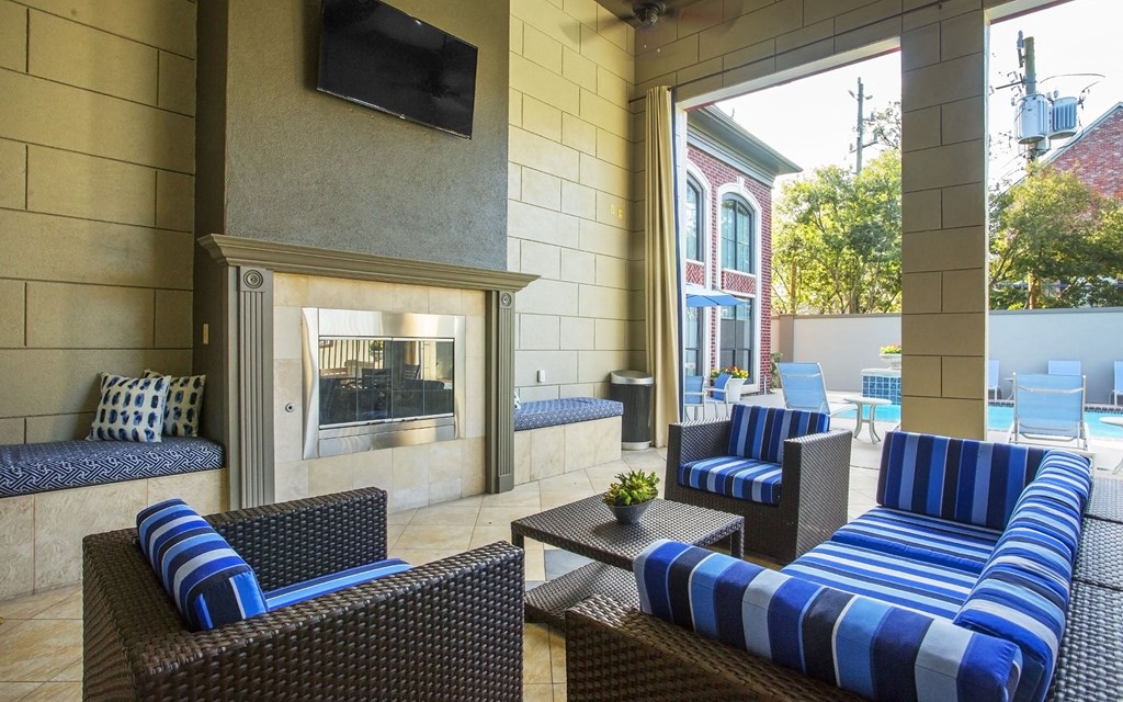 A patio with a fireplace and blue striped couches.