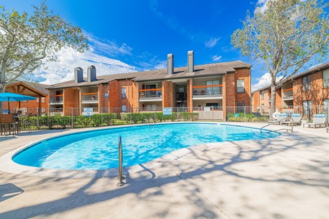 A large swimming pool in front of a red brick building.