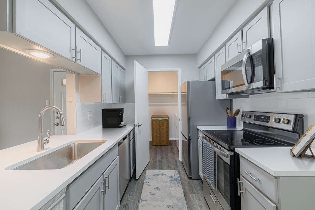 A kitchen with white cabinets and a black fridge.