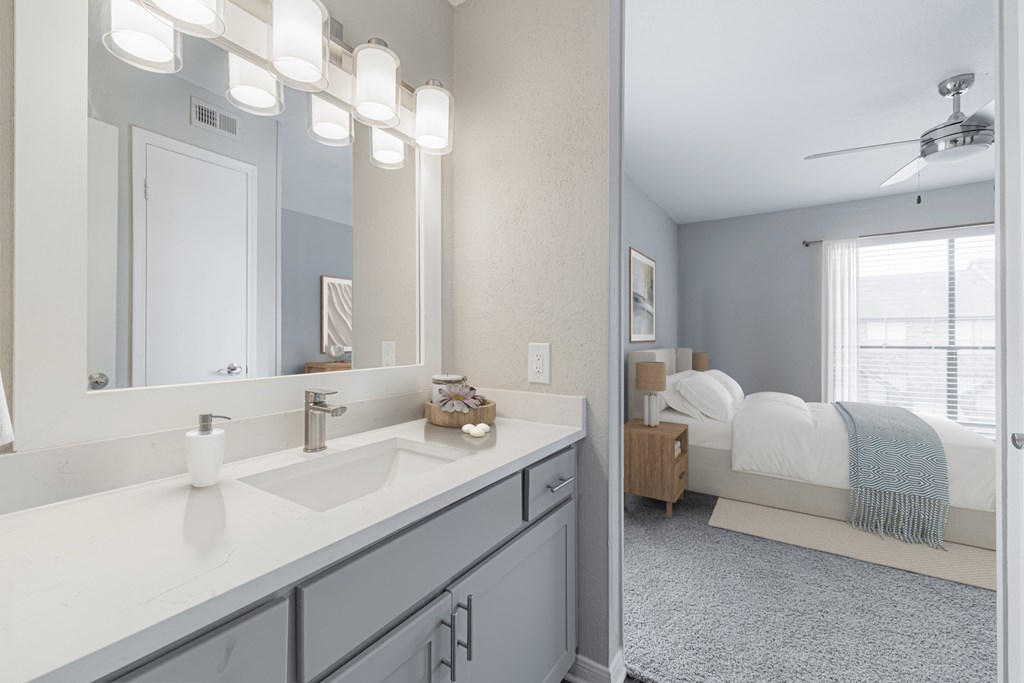 A bathroom with a vanity, a bed, and a ceiling fan.