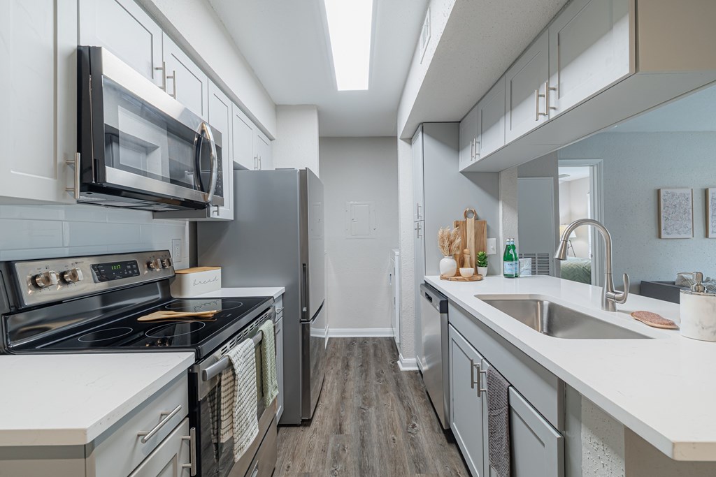 A modern kitchen with a stove, microwave, and refrigerator.