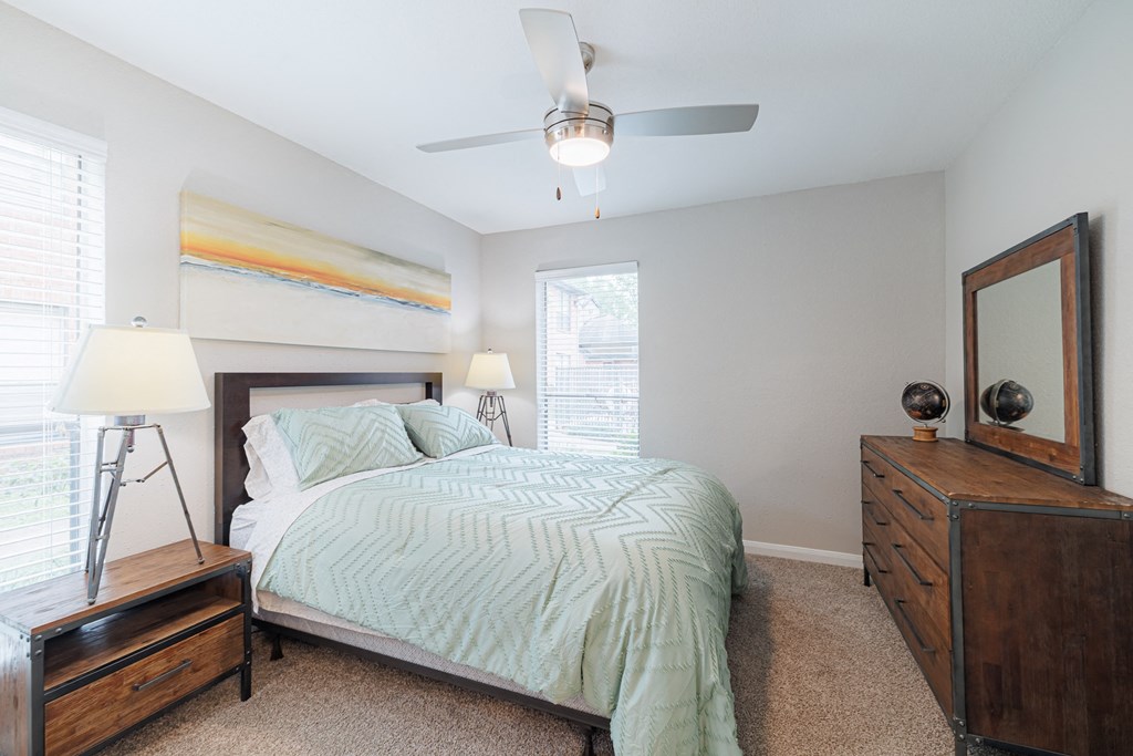A bedroom with a bed, nightstand, and a ceiling fan.