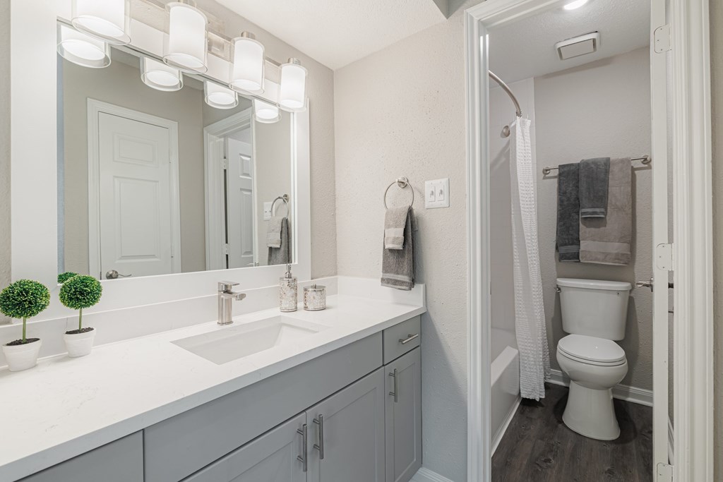 A bathroom with a white counter top and a white toilet.